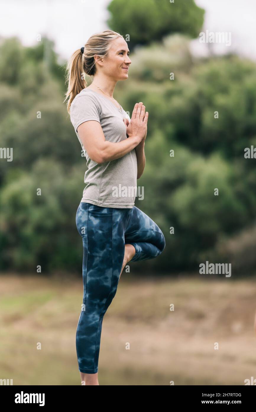 Frau, die draußen Yoga macht, umgeben von Natur Stockfoto