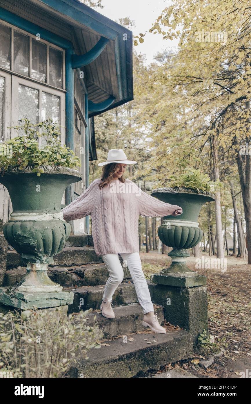 Blondine in einem weißen Hut geht an einem Herbsttag im Park Stockfoto