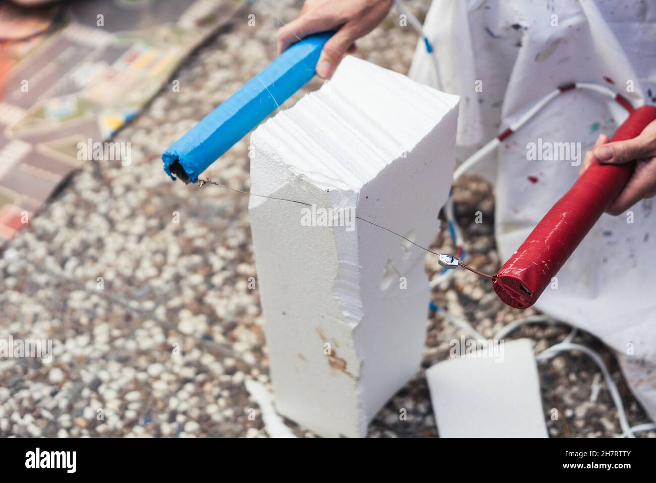 Frau hackt einen Block aus Polystyrol mit einem heißen Stahlkabel im Freien Stockfoto