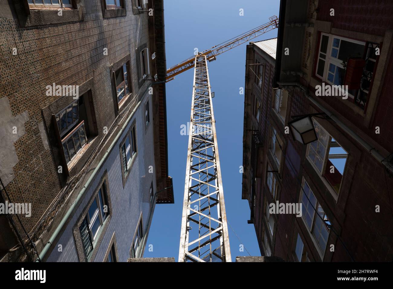 An der Rua de Trás in Porto, Portugal, verteilt sich ein Baukran auf Wohngebäude, die derzeit renoviert werden. Stockfoto