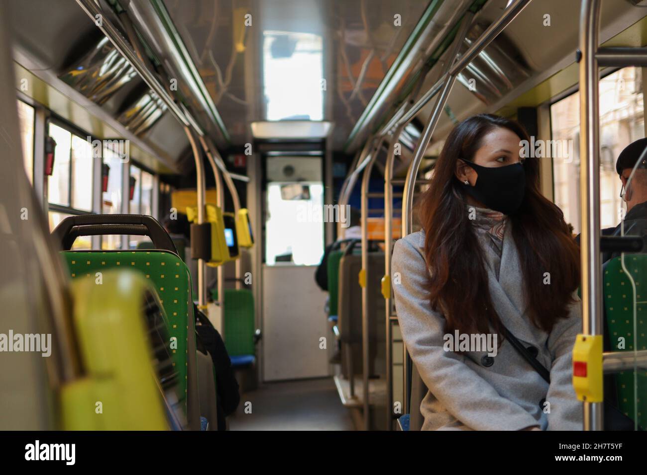 Eine junge Frau mit Atemschutzmaske reist aufgrund einer Coronavirus-Pandemie mit öffentlichen Verkehrsmitteln. Sicherheitsvorkehrungen in Bussen Stockfoto