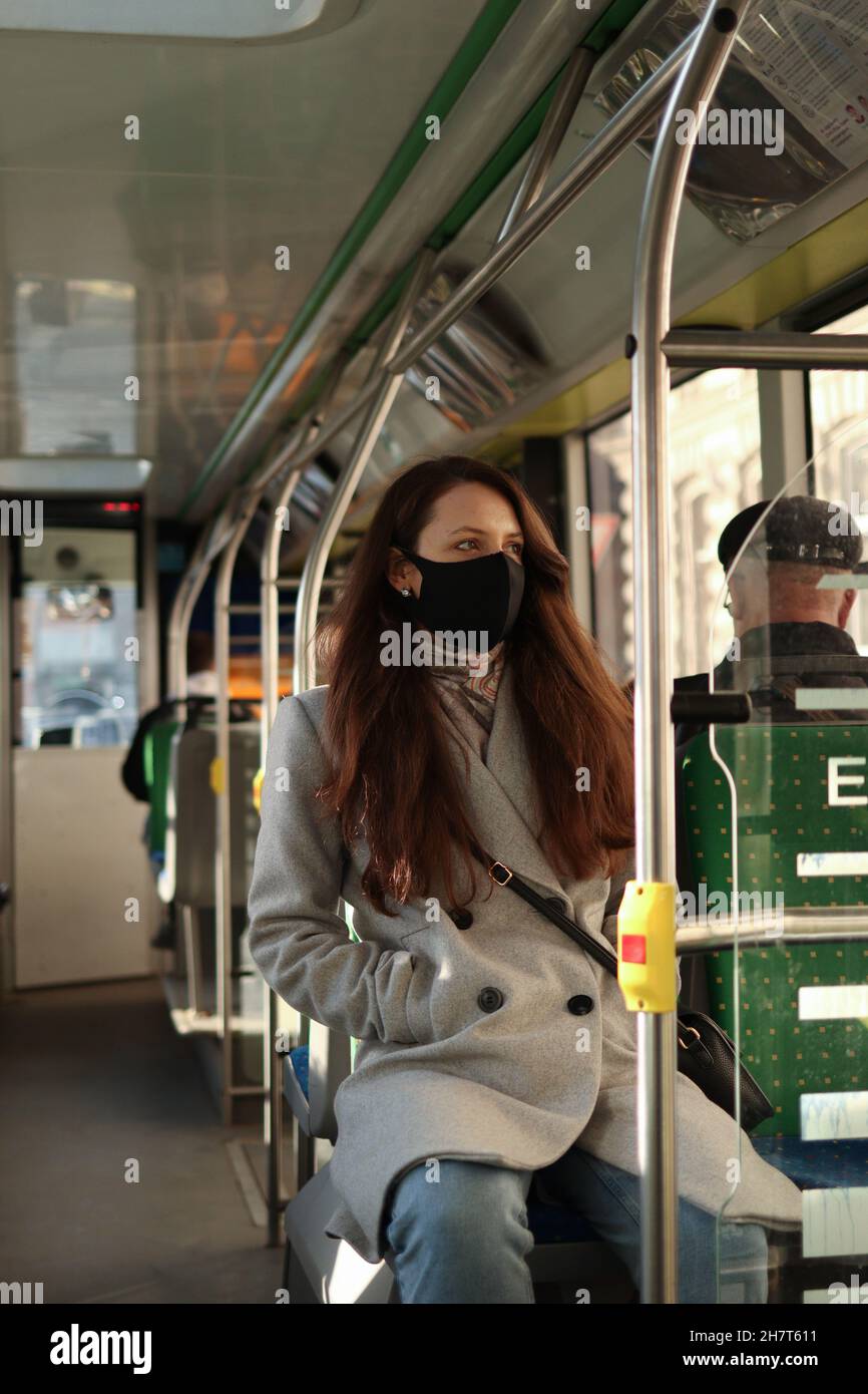 Eine junge Frau mit Atemschutzmaske reist mit öffentlichen Verkehrsmitteln. Sicherheitsvorkehrungen in Bussen Stockfoto