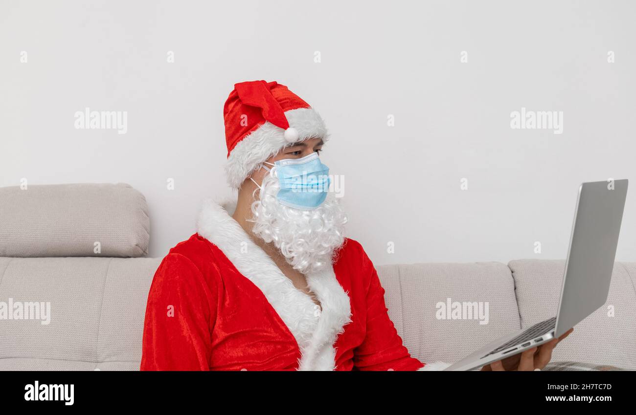 Mann als Weihnachtsmann mit Laptop gekleidet Stockfoto