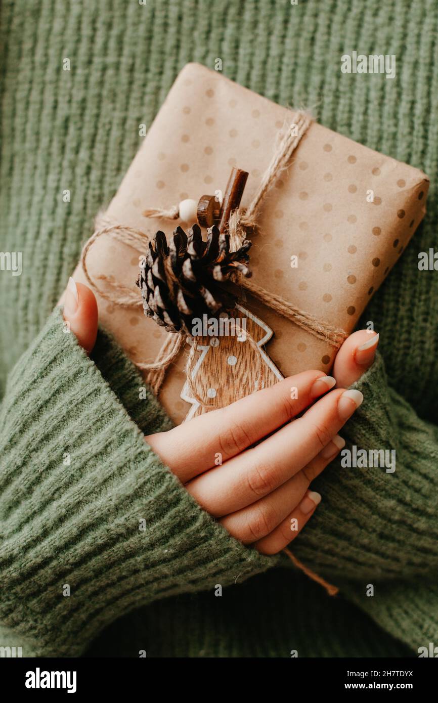 Weibliche Hände halten schöne Geschenkbox. Frau geben eingewickelt in Bastelpapier präsent. Kuscheliges Geschenkpapier-Design Stockfoto