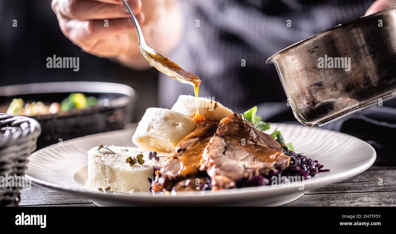 Lebensmittel dekorieren Hand eines Küchenchefs gießt Sauce über herzhafte Speisen aus Fleisch, Knödel und Kohl. Stockfoto