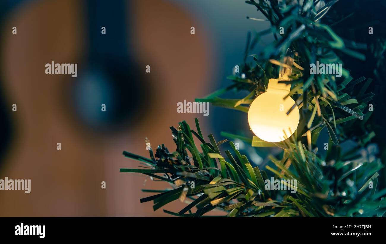 Ein Licht auf einem Weihnachtsbaum mit verschwommener klassischer Gitarre im Hintergrund Stockfoto