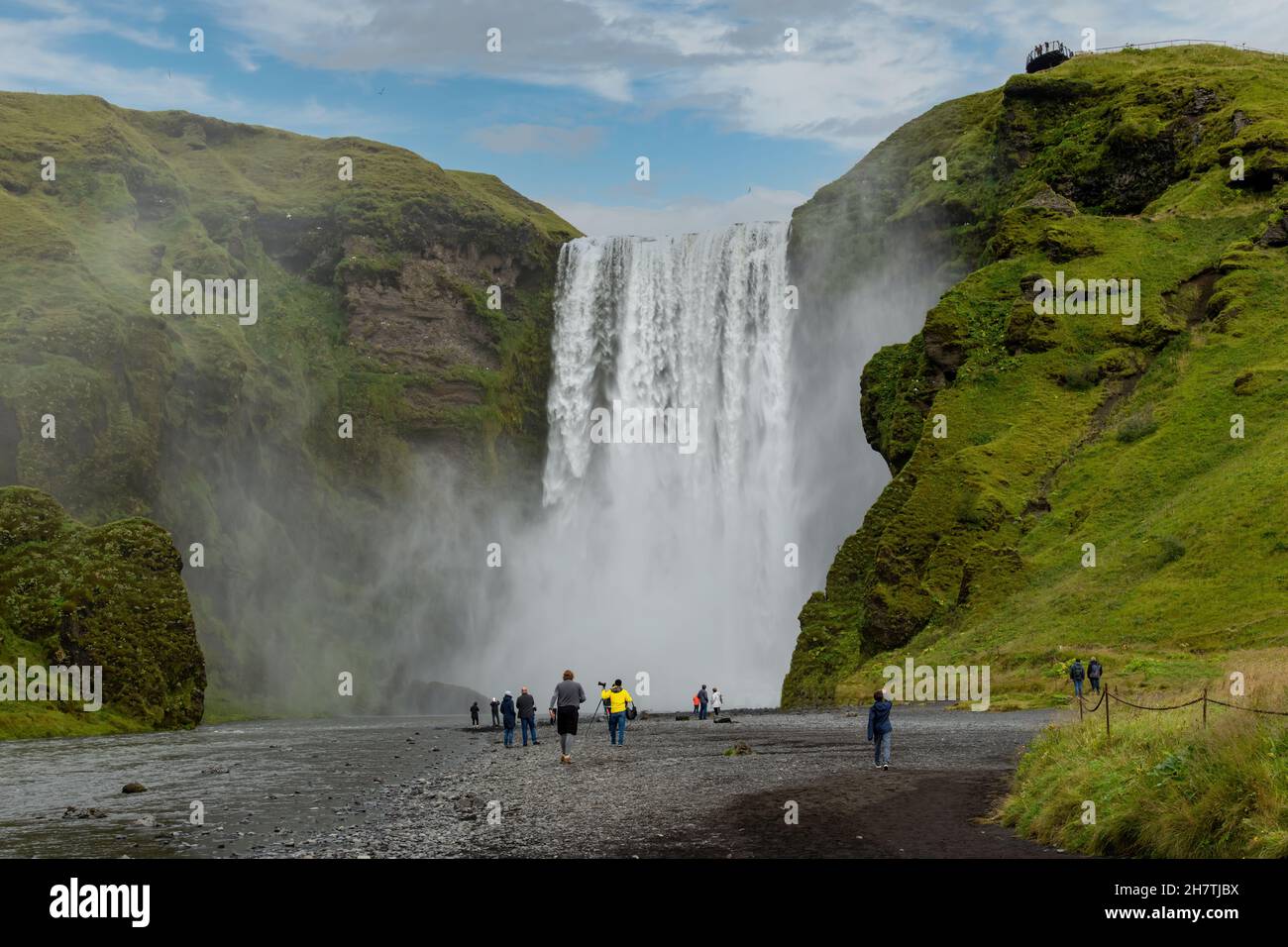 Blick vom unteren Teil des Seljalandsfoss-Wasserfalls in Island mit seinem Ursprung im Vulkangletscher Eyjafjallajokull; zahlreiche Menschen gehen zu Fuß Stockfoto