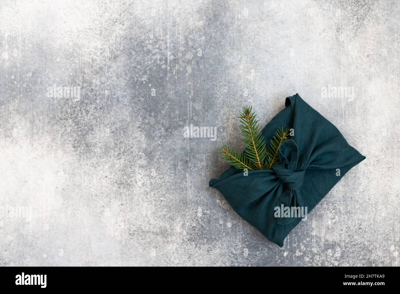 Geschenk im Furoshiki-Stil für Weihnachten oder Neujahr auf weißem Hintergrund. Flach liegend. Speicherplatz kopieren. Stockfoto