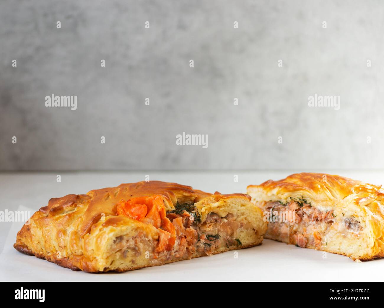 Traditioneller russischer Fischkuchen aus Hefeteig, gefüllt mit Lachs auf grauem Hintergrund. Speicherplatz kopieren. Stockfoto