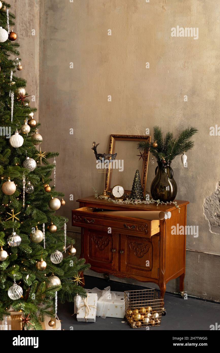 Hintergrund zum neuen Jahr. Weihnachtliche Einrichtung im Loft-Zimmer. Beleuchtung, antike Möbel, Kerzen und heiße Innenbeleuchtung, Girlanden in der Nähe des Weihnachtsbaums mit Stockfoto