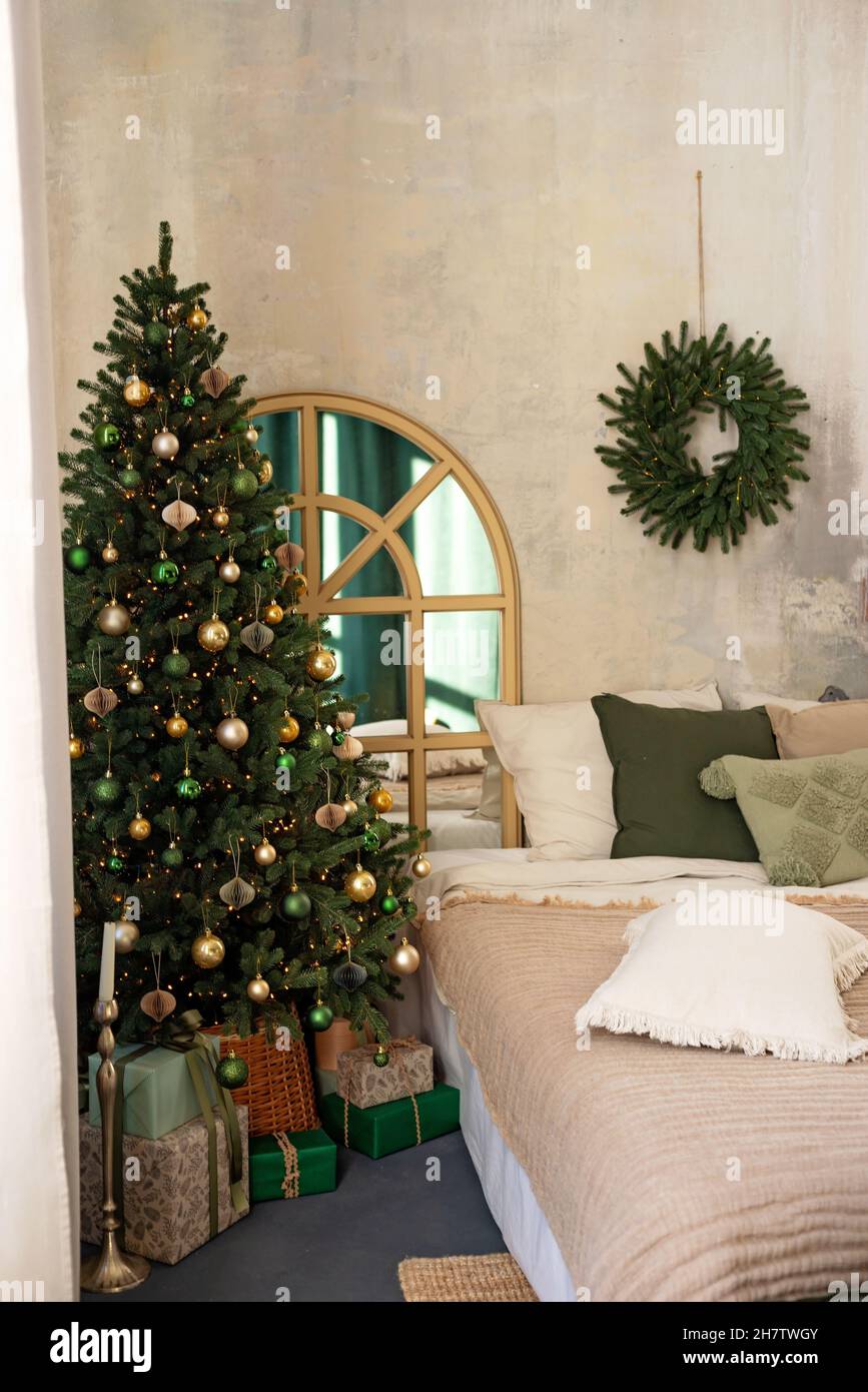 Hintergrund zum neuen Jahr. Weihnachtliche Einrichtung im Loft-Zimmer. Beleuchtung, Geschenke, Kerzen und heiße Innenbeleuchtung. Weihnachtsbäume mit Geschenken. Weicher, selektiver Fokus. Stockfoto