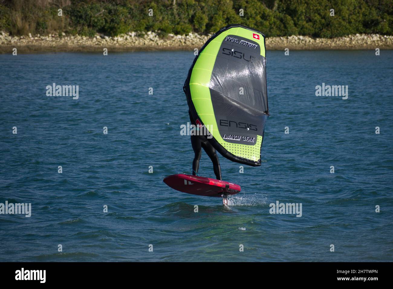 Person Windsurf, die auf dem Fluss Adur in Shoreham mit hoher Geschwindigkeit im Flugzeug unterwegs ist, bevor sie in den Wind dreht. Stockfoto