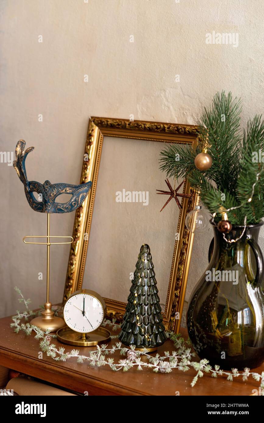 Hintergrund zum neuen Jahr. Weihnachtliche Einrichtung im Loft-Zimmer. Karnevalsmaske, Uhr, antike Möbel, Baum. Weicher, selektiver Fokus. Stockfoto