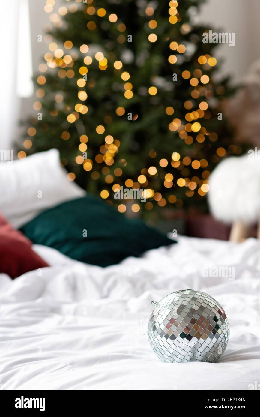 Hintergrund zum neuen Jahr. Spiegelkugel vor dem Hintergrund der Bokeh Lichter des Weihnachtsbaums. Weicher, selektiver Fokus. Stockfoto