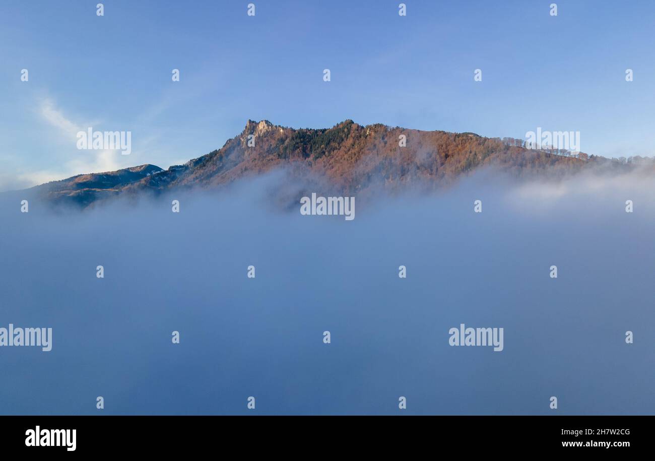Aschau, Deutschland. 25th. November 2021. Das Zellerhorn steigt aus der dichten Nebeldecke in den blauen Himmel. Kredit: Peter Kneffel/dpa/Alamy Live Nachrichten Stockfoto