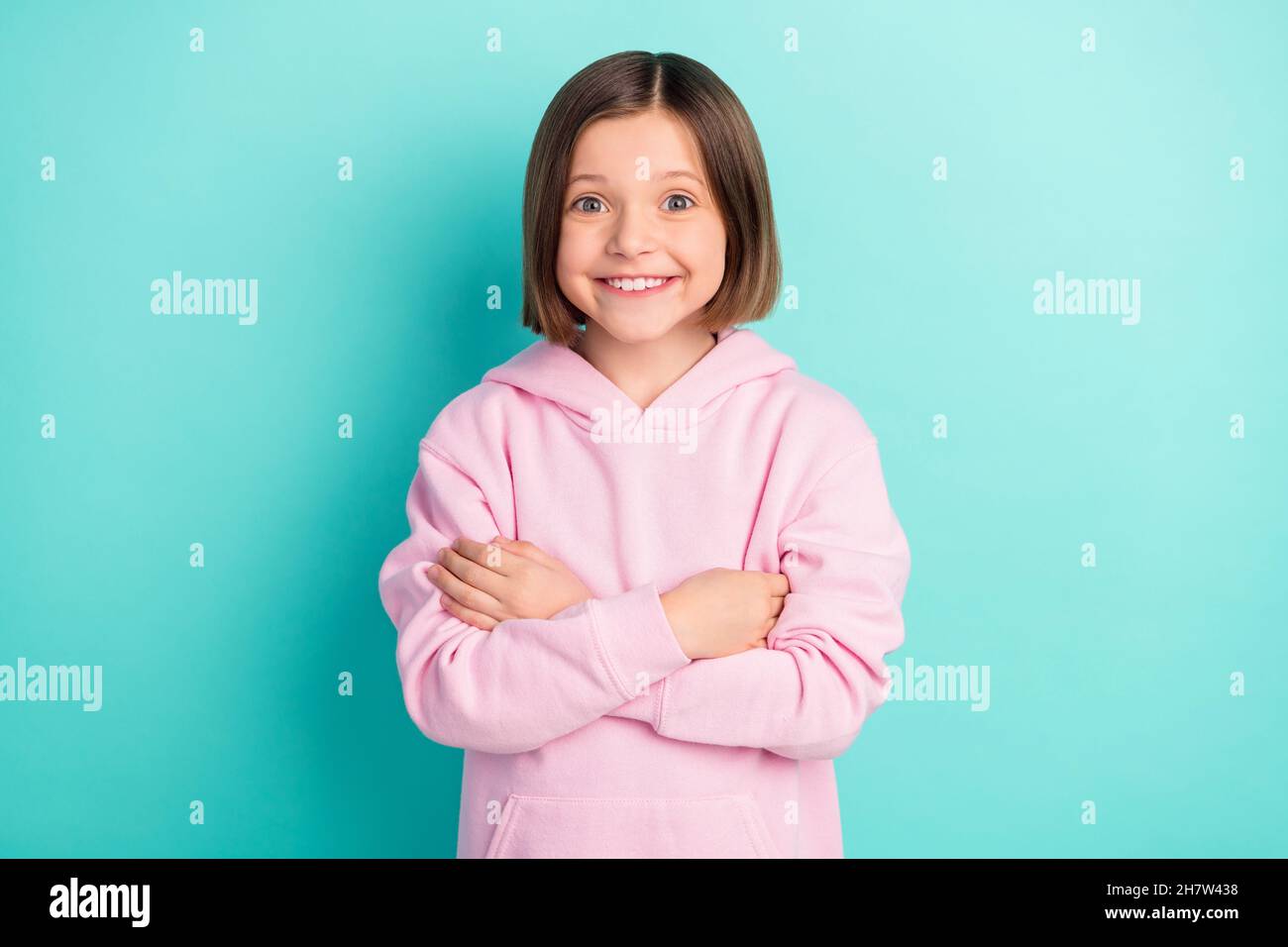 Foto von bob Frisur kleines Mädchen gekreuzte Arme tragen rosa Sportkleidung isoliert auf blauem Hintergrund Stockfoto