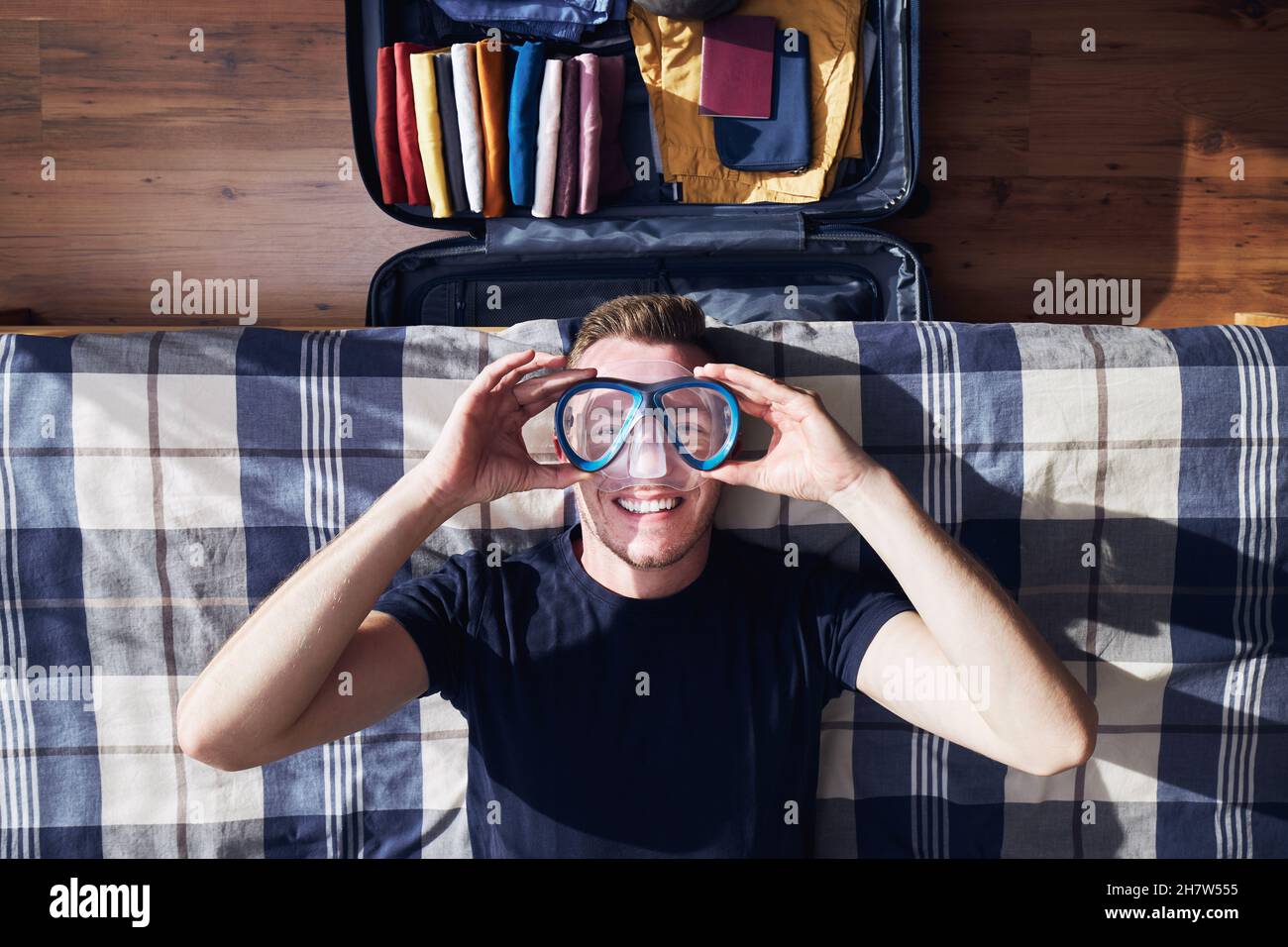 Lustiges Porträt eines glücklichen jungen Mannes beim Packen Koffer und Planung Reise-Abenteuer. Stockfoto