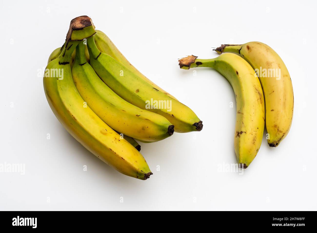 Ein Haufen halbreifer Bananen auf weißem Hintergrund. Stockfoto
