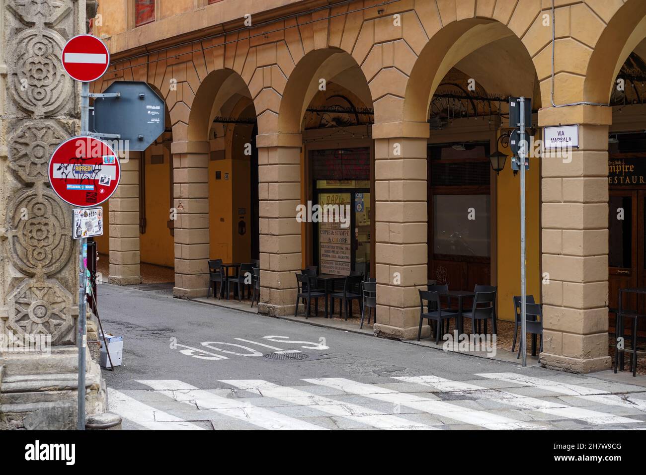 Restaurant ohne Kunden in Bologna während der Corona-Pandemie. Leere Tische und Stühle auf dem Bürgersteig in der Arkade davor. Stockfoto