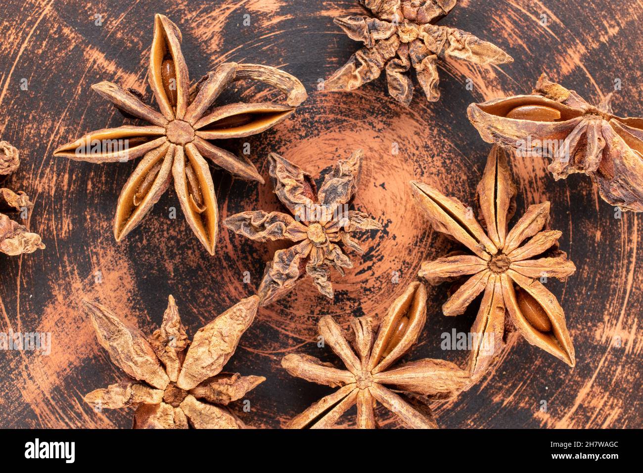 Mehrere Sterne von trocken duftendem Sternanisgestein auf einer Tonplatte, Nahaufnahme, Draufsicht. Stockfoto