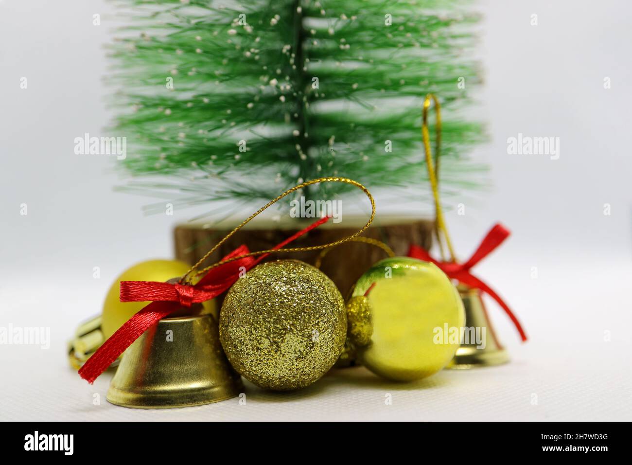 Handgefertigter Weihnachtsbaum mit goldfarbenen Glocken und Kugeln, grüner Weihnachtsbaum, Glocken mit roten Schleifen, Weihnachtsdekoration auf weißem Hintergrund Stockfoto
