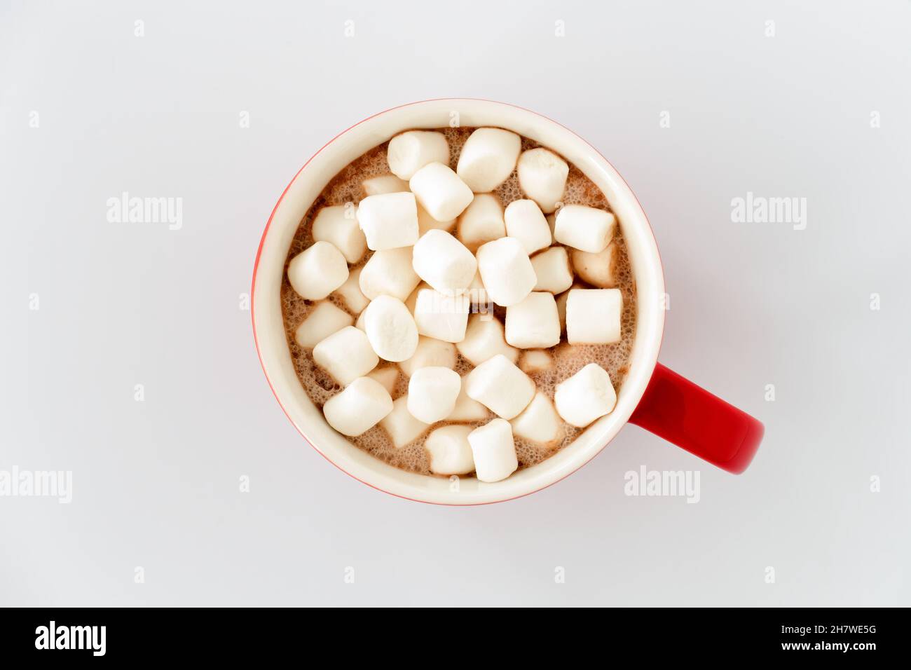 Draufsicht auf roten Becher mit heißer Schokolade und Mini-Marshallows isoliert auf weiß. Stockfoto