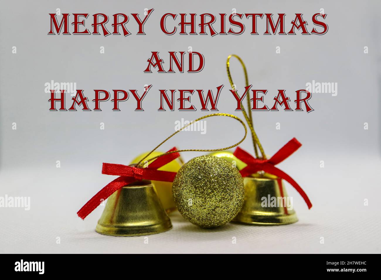 Goldfarbene Glocken und Kugeln, Glocken mit roten Schleifen, Weihnachtsdekoration auf weißem Hintergrund, Neujahrsdekoration, Weihnachtskarte, Stockfoto