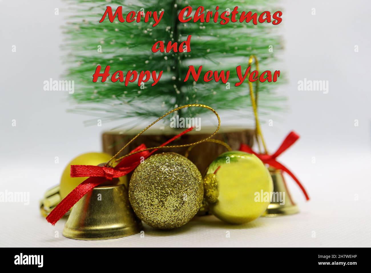 Handgefertigter Weihnachtsbaum mit goldfarbenen Glocken und Kugeln, grüner Weihnachtsbaum, Glocken mit roten Schleifen, Weihnachtsdekoration auf weißem Hintergrund, New Y Stockfoto