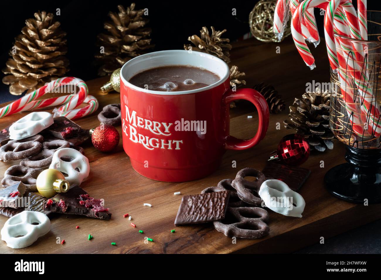 Ein Becher heiße Schokolade, umgeben von Weihnachtsschokolade und Zuckerstöcken. Stockfoto