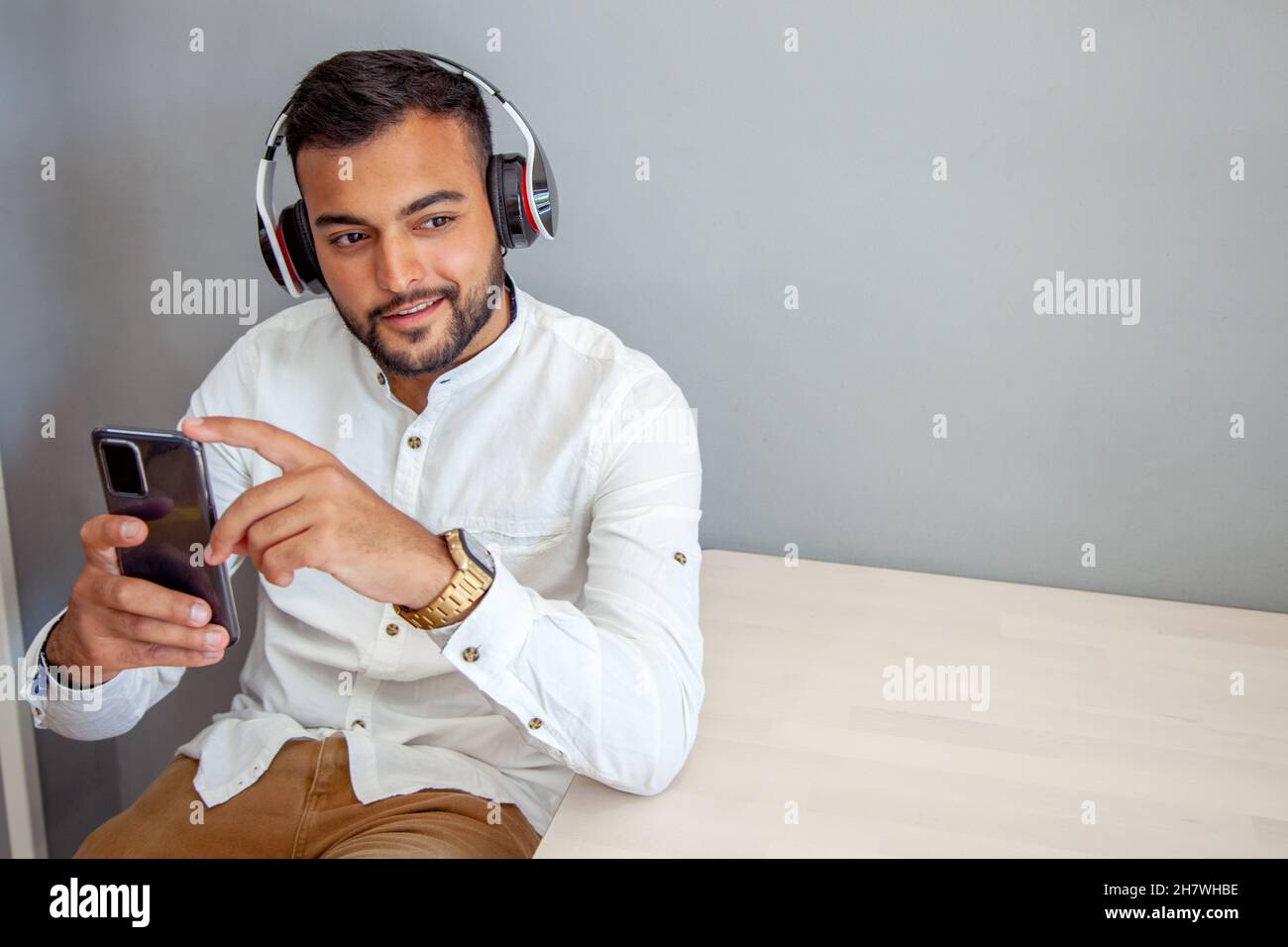 Junge hört Musik mit Kopfhörern. Mann mit Handy. Mann im Café, der auf das Handy schaut. Lifestyle. Arbeitspause. Stockfoto
