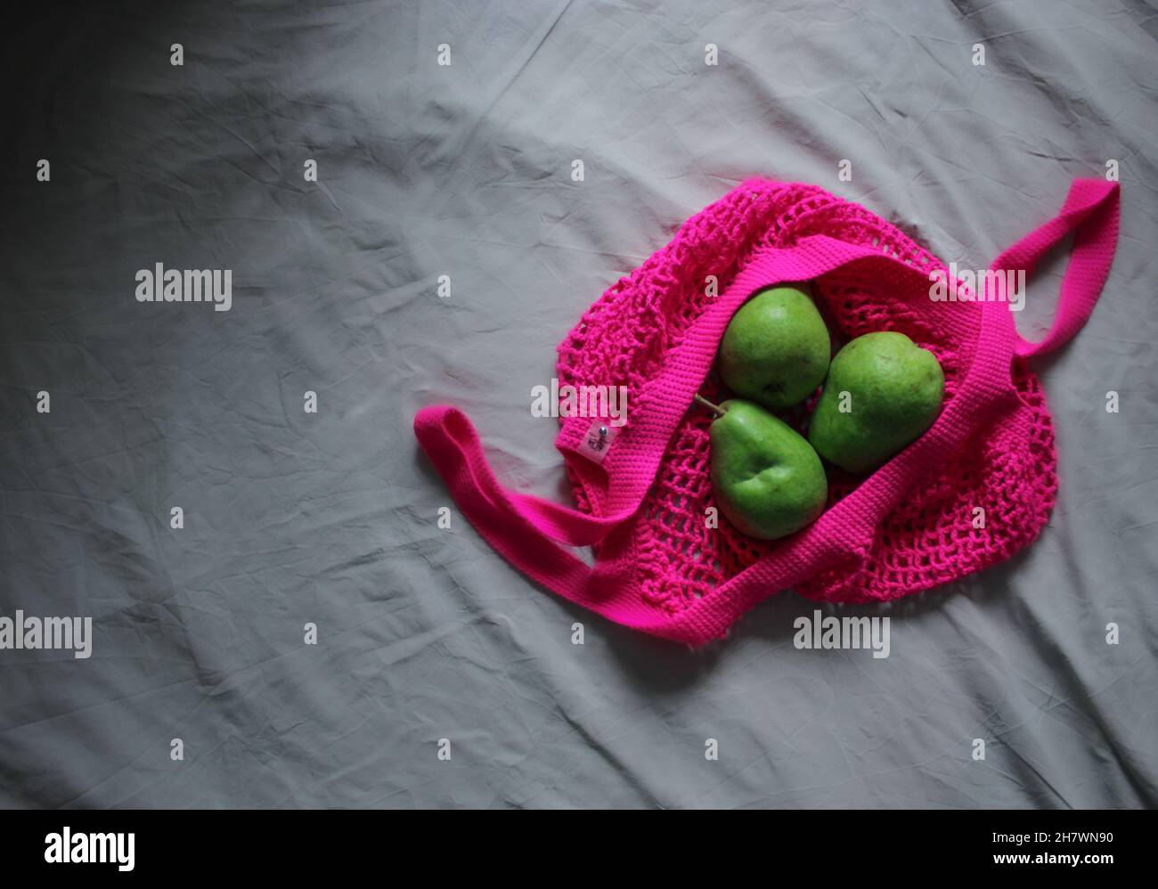 Grüne Birnen in der neonrosa Einkaufstasche Stockfoto