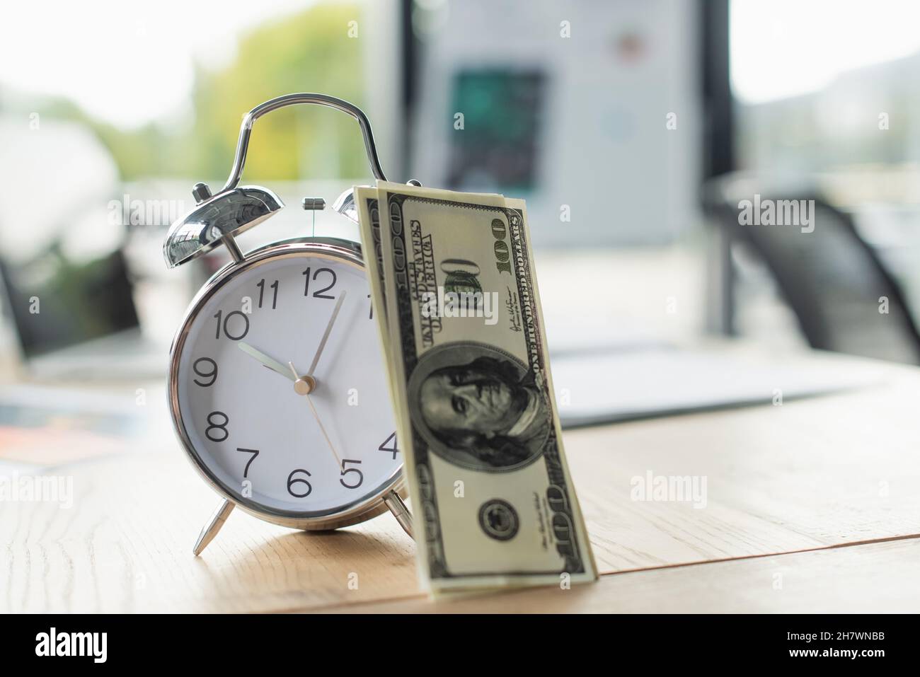 KIEW, UKRAINE - 22. SEPTEMBER 2021: Dollar-Banknoten in der Nähe von Retro-Wecker auf dem Schreibtisch, Anti-Korruptions-Konzept Stockfoto