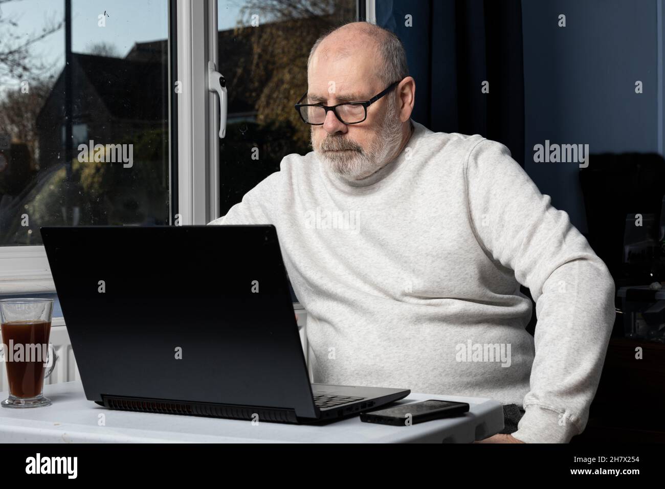 Mann, der von einem Heimbüro aus an einem Laptop arbeitet. Stockfoto