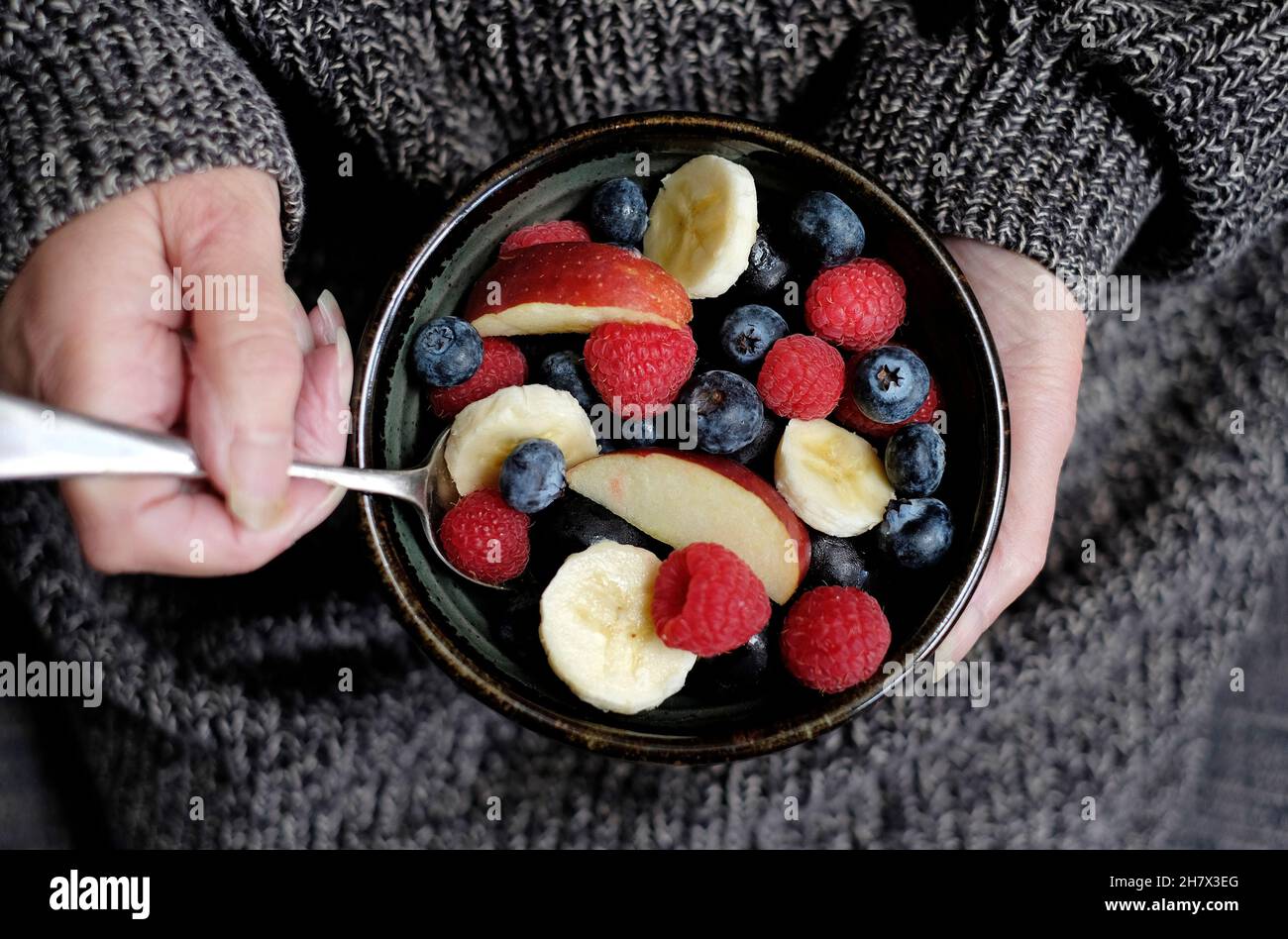 Person hält rustikale Schüssel voll von gesunden Obst Frühstück Stockfoto
