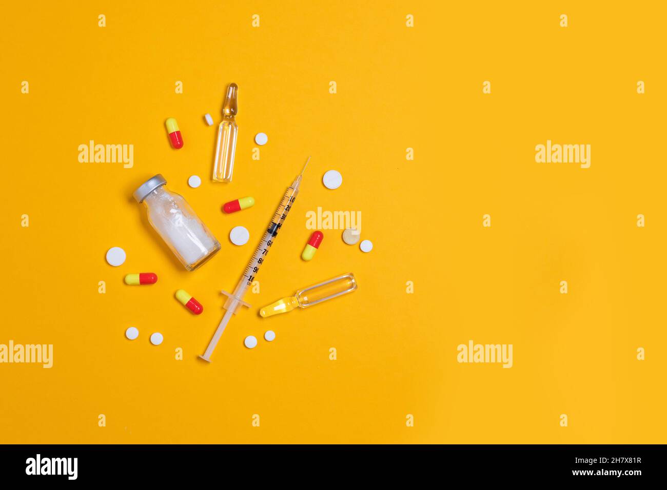 Impfstoff und Spritze, verschiedene pharmazeutische Medikamente Pillen, Tabletten und Kapseln gelber Hintergrund. Gesundheitswesen und medizinisches Konzept. Stockfoto