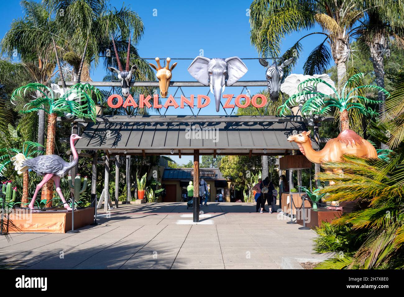 Oakland, Kalifornien - 12. November 2021: Eintritt in den Oakland Zoo an einem sonnigen Tag, mit Tierdarstellungen und Pflanzen auf dem Gehweg. Stockfoto