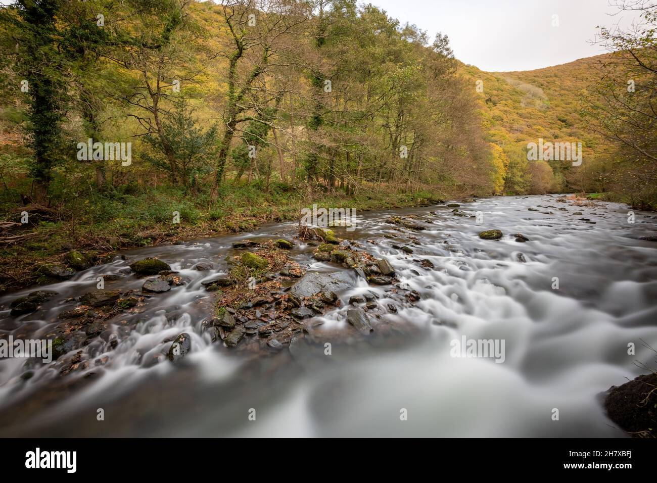 Langzeitbelichtung des East Lyn River, der im Herbst durch das Doone Valley bei Watersmeet im Exmoor National Park fließt Stockfoto