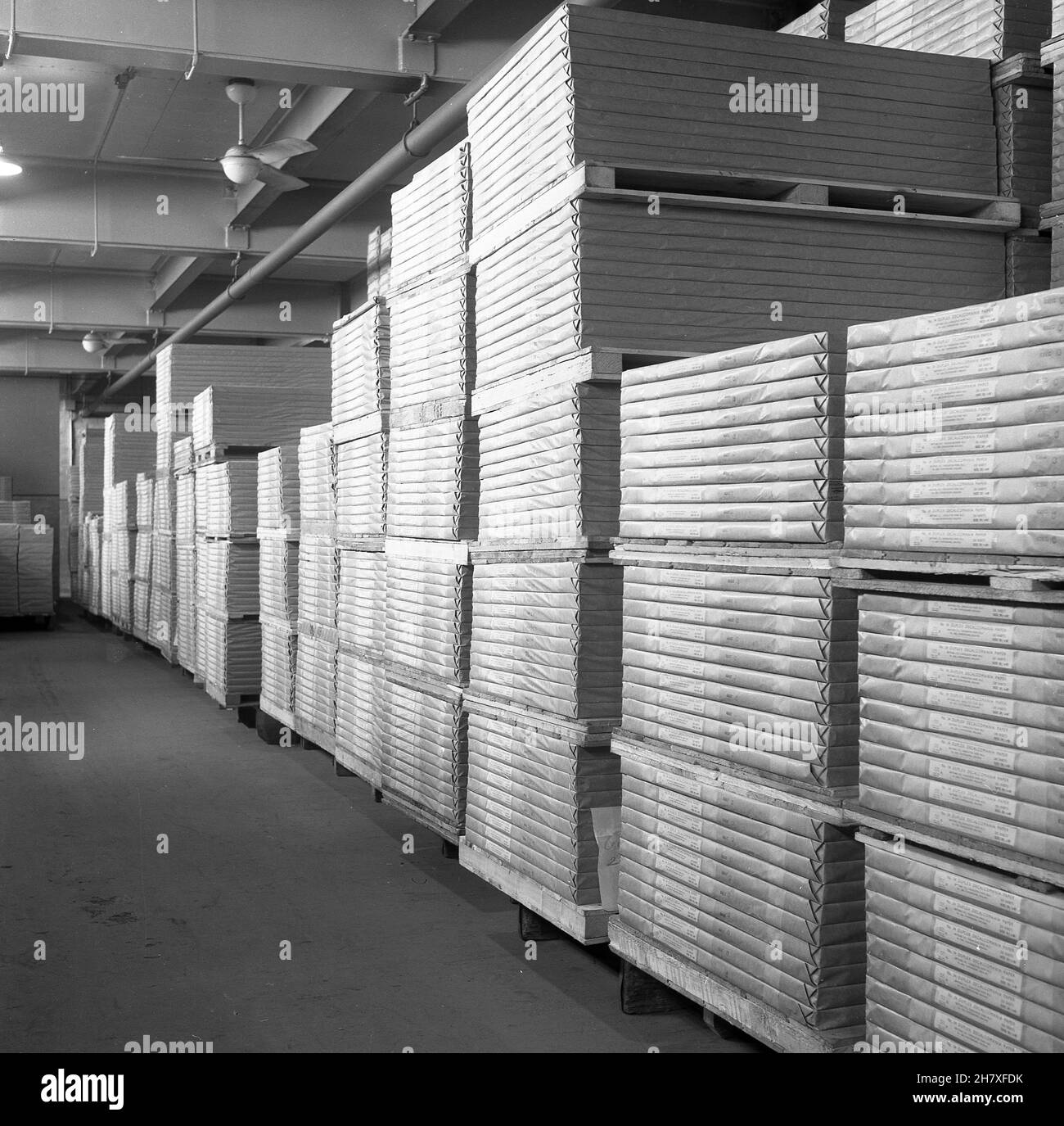 1950s, historisch, in einem Lagerhaus, auf Holzstützen, Stapeln von fertigen Papier, verpackt und beschriftet in der Papierfabrik von Brittains Limited, Cheddleton, England, Großbritannien. Das Papier wurde ursprünglich von Hand hergestellt, aber mit der Erfindung der Papiermaschine durch die Foudrinier-Brüder wurde die Industrie mechanisiert und die Briten wurden der Nachfolger der Brüder, die in Hanley eine Mühle betrieben. Thomas Brittain spielte eine wichtige Rolle in der Geschichte der Papierherstellung. Stockfoto