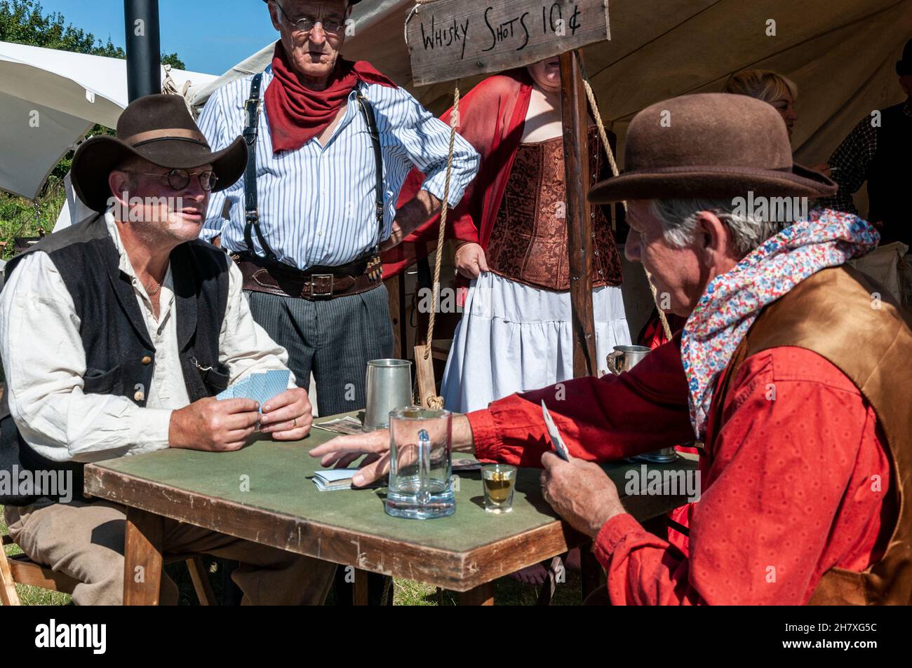 Nachbildung eines Kartenspiels aus der „Cowboy-Ära“ des Wilden Westens USA. Nachstellung des amerikanischen Westens. Karten, geschossenes Glas auf dem Kartentisch Stockfoto