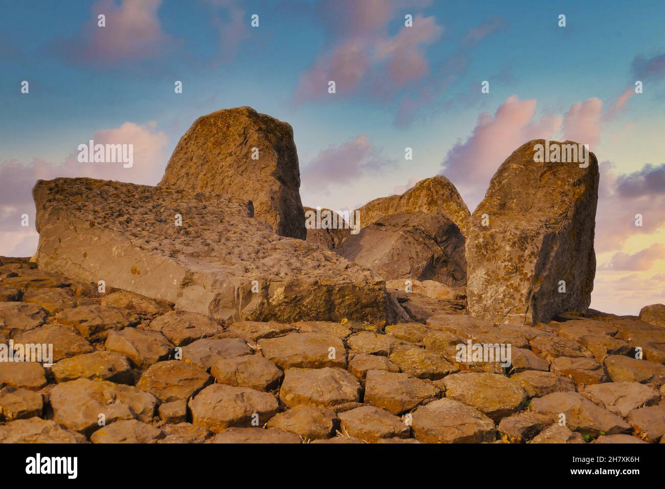 Regelmäßig geformte Basaltblöcke und riesige Felsbrocken auf einem Seedeich im Norden der Niederlande in der Abendsonne. Stockfoto