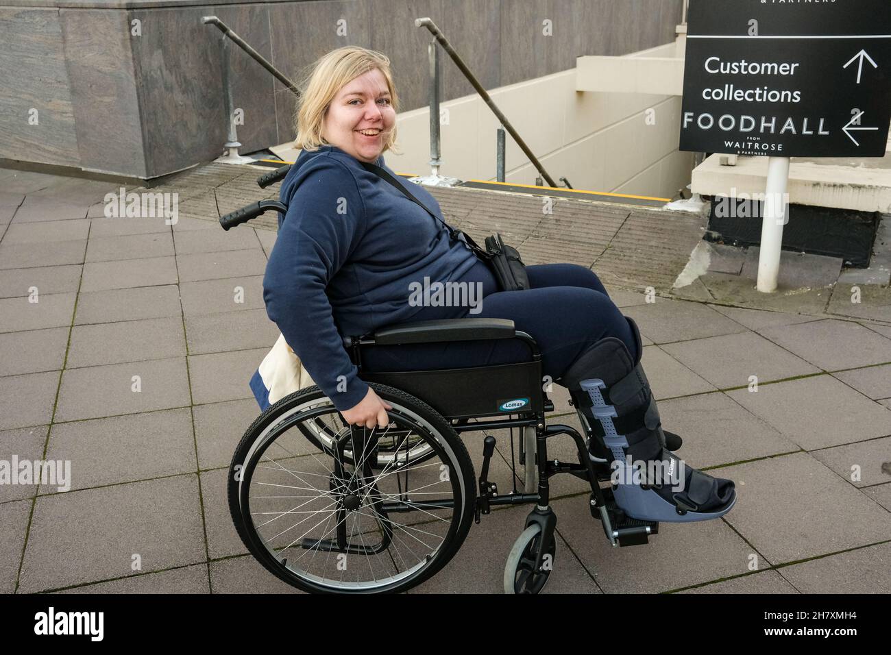 Junge Dame in einem Rollstuhl und Luftstiefel, nachdem sie an zwei Stellen einen gebrochenen Fuß erlitten hatte Stockfoto