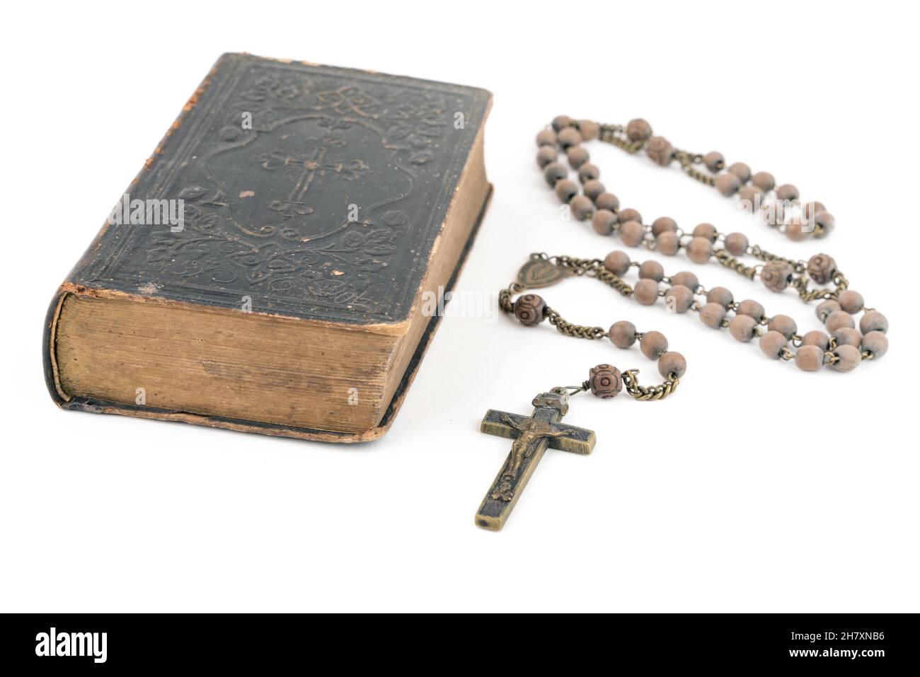 Große Studioaufnahme einer sehr alten, alten Heiligen Bibel mit vielen Ornamenten auf dem Cover und gelben Seiten und einem alten Rosenkranz auf weißem Hintergrund Stockfoto