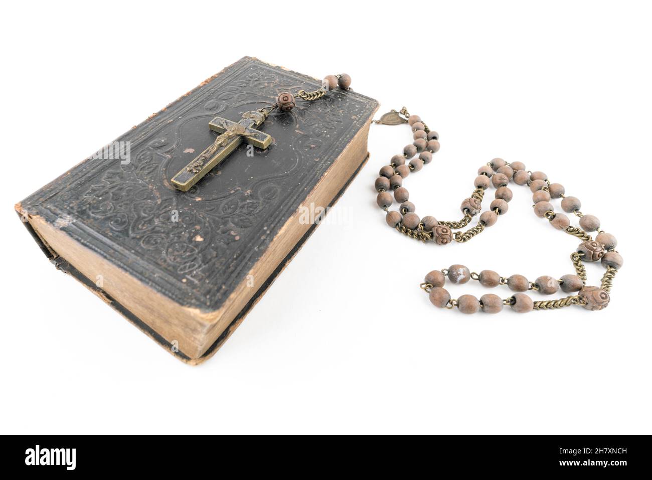 Große Studioaufnahme einer sehr alten, alten Heiligen Bibel mit vielen Ornamenten auf dem Cover und gelben Seiten und einem alten Rosenkranz auf weißem Hintergrund Stockfoto