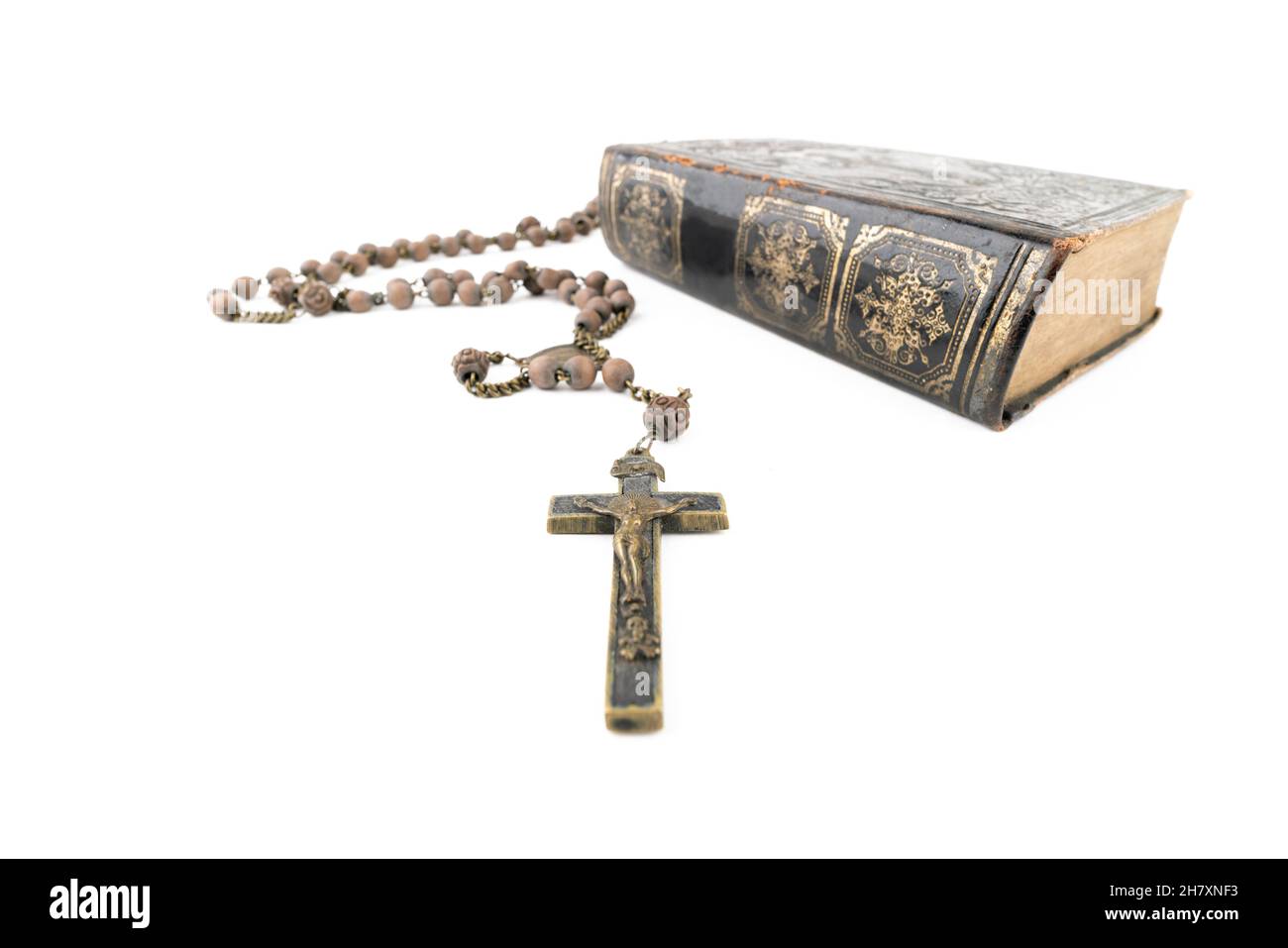 Große Studioaufnahme einer sehr alten, alten Heiligen Bibel mit vielen Ornamenten auf dem Cover und gelben Seiten und einem alten Rosenkranz auf weißem Hintergrund Stockfoto