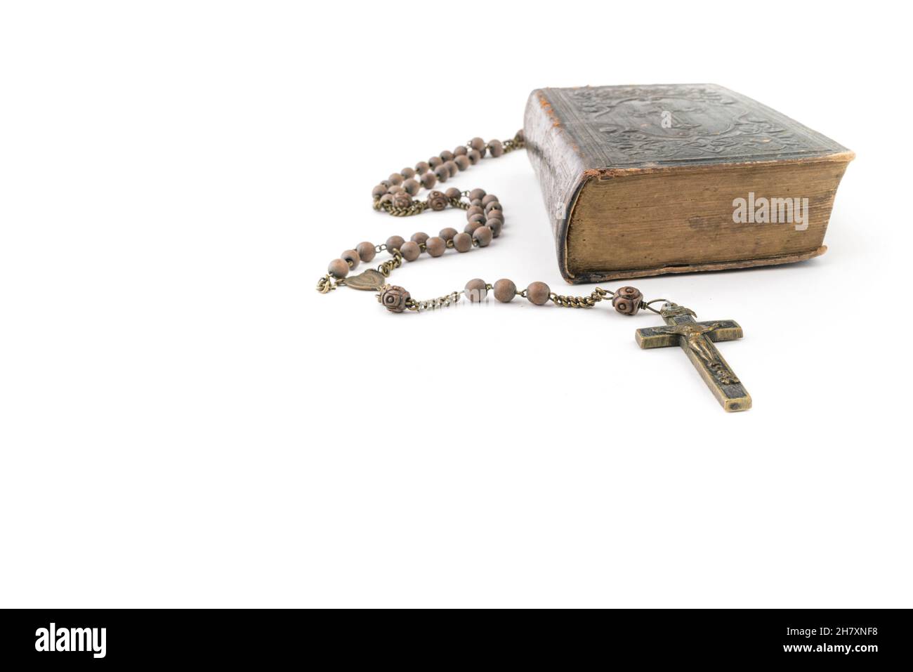 Große Studioaufnahme einer sehr alten, alten Heiligen Bibel mit vielen Ornamenten auf dem Cover und gelben Seiten und einem alten Rosenkranz auf weißem Hintergrund Stockfoto