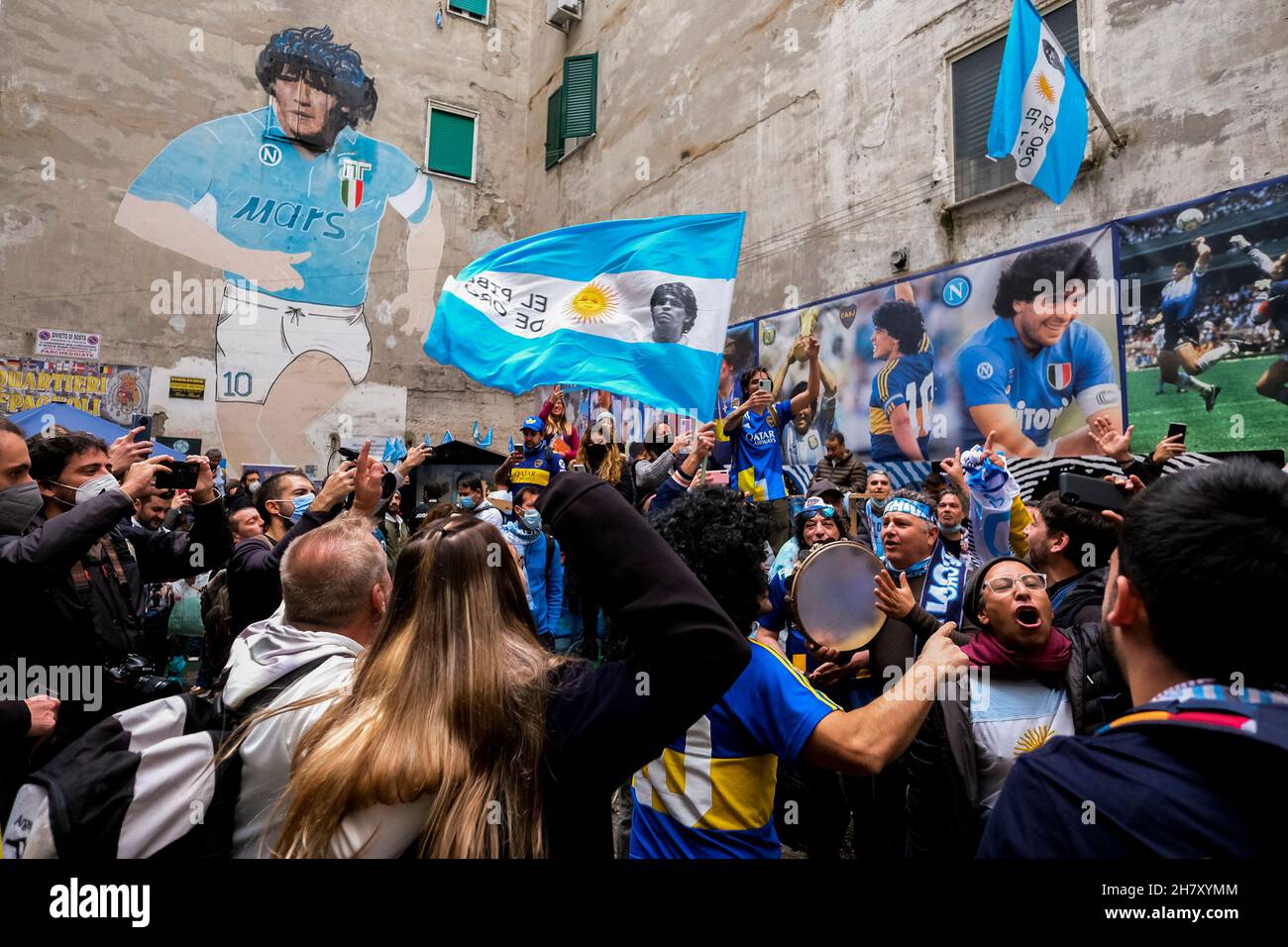 Genau ein Jahr nach dem Tod von Diego Armando Maradona treffen sich Napoli-Fans und Boca Juniors-Fans, die zu diesem Anlass nach Neapel kamen, um vor dem Wandgemälde, das Diego Armando Maradona gewidmet ist, an ihr gemeinsames Idol zu erinnern. Stockfoto