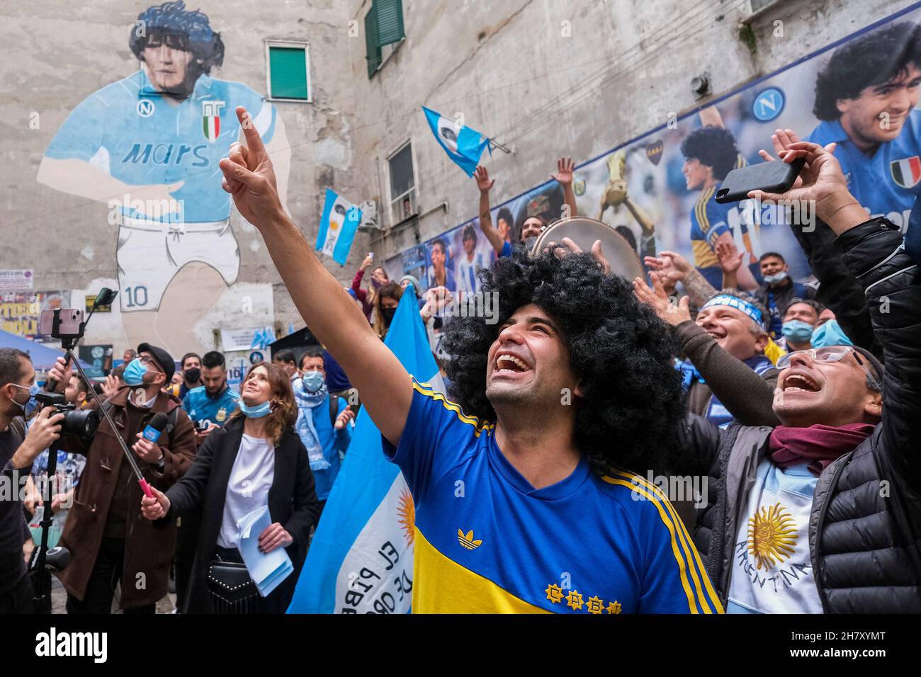 Genau ein Jahr nach dem Tod von Diego Armando Maradona treffen sich Napoli-Fans und Boca Juniors-Fans, die zu diesem Anlass nach Neapel kamen, um vor dem Wandgemälde, das Diego Armando Maradona gewidmet ist, an ihr gemeinsames Idol zu erinnern. Stockfoto