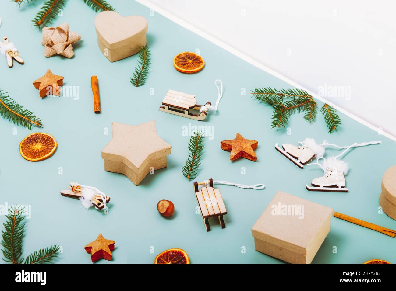 Weihnachten Seitenansicht grüner Hintergrund mit Tannenzweigen, umweltfreundlichen Pappkartons, Holzspielzeug, Zimt, getrockneten Orangen und weißem Dreieck Cop Stockfoto