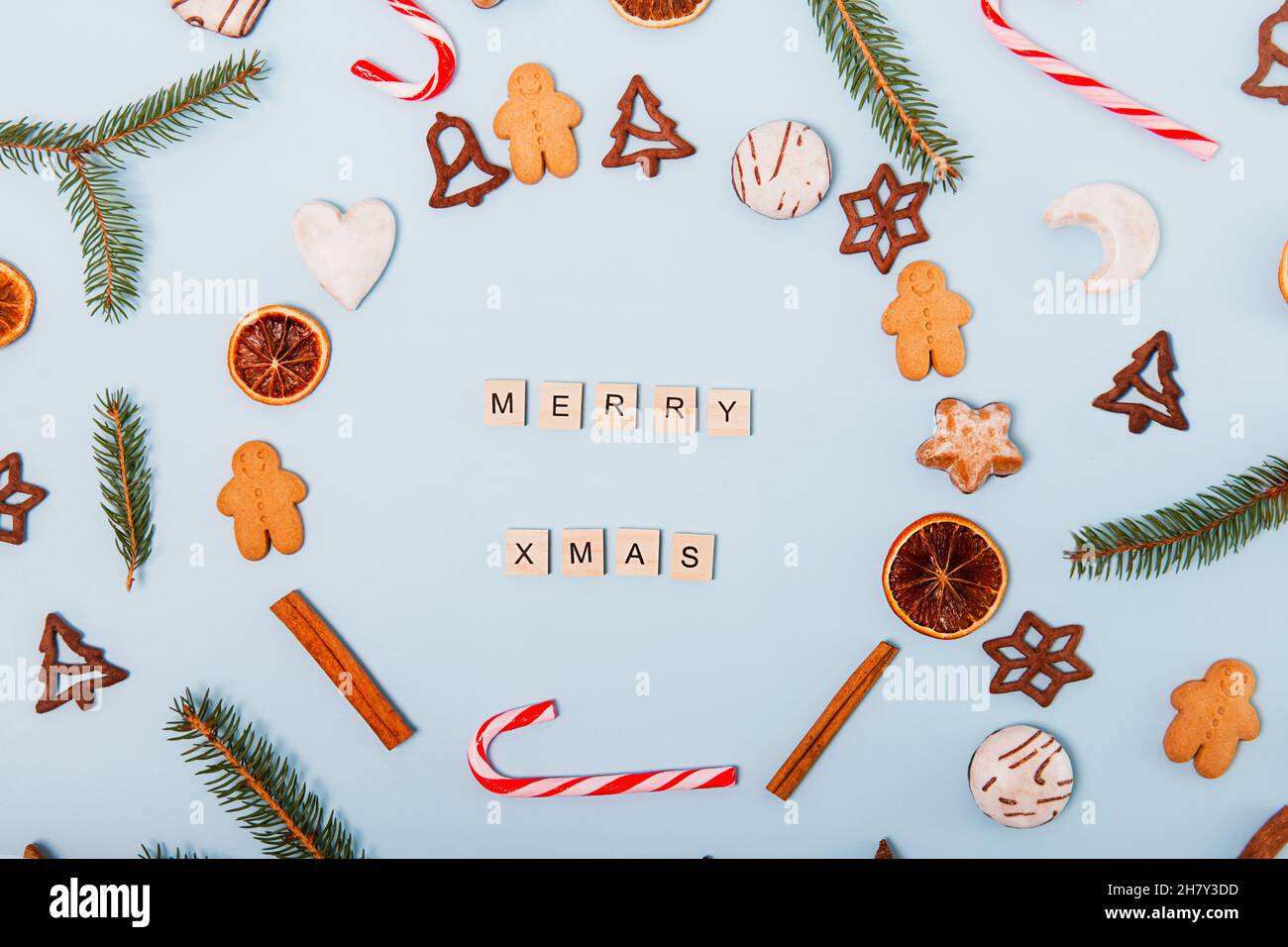 Draufsicht Weihnachtskranz aus verschiedenen Sorten von Weihnachtsgebäck, Süßigkeiten, Bonbons, getrockneten Orangen, Lebkuchenbonbons auf dem blauen Backgr Stockfoto