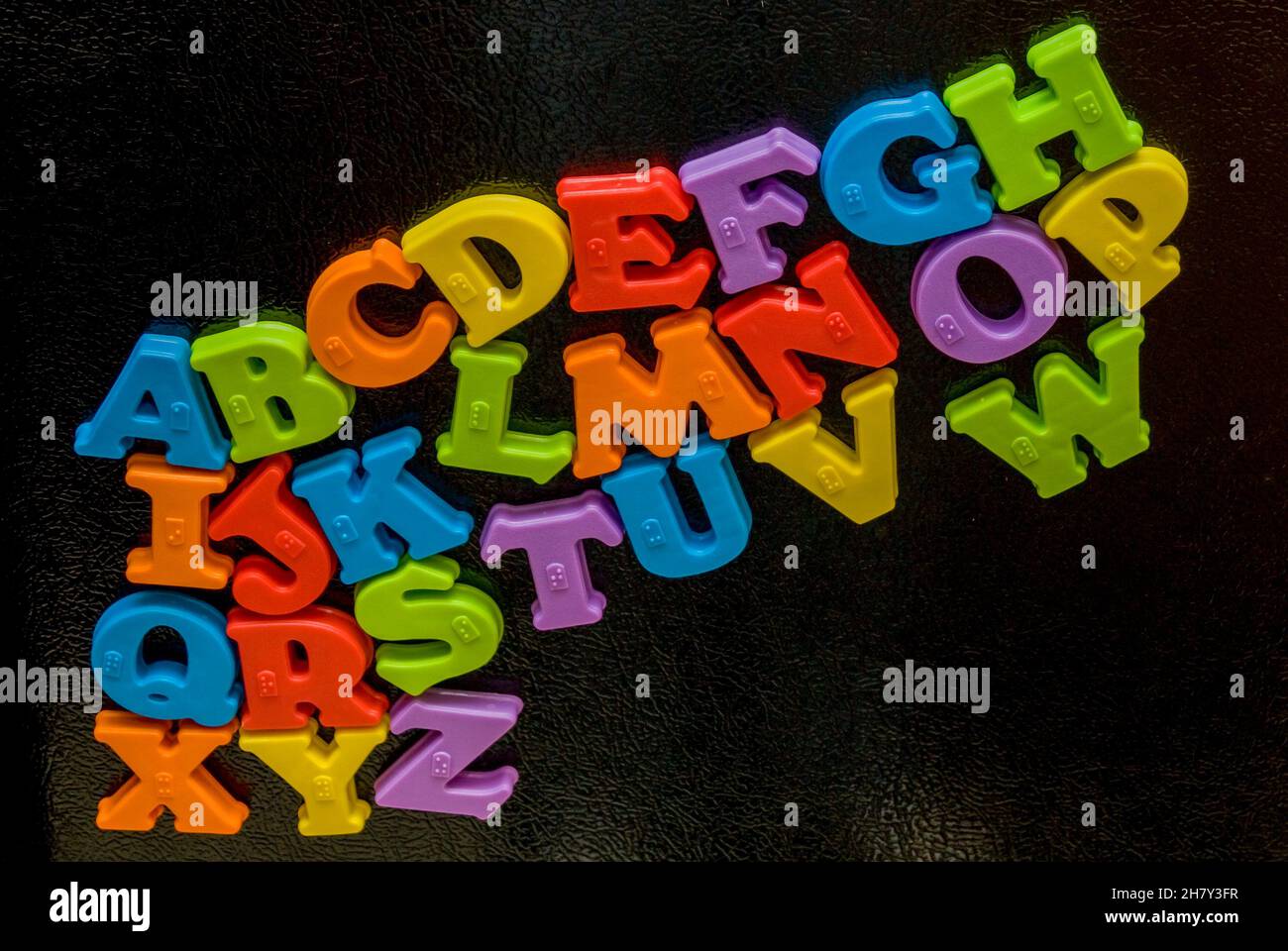 Magnetische Buchstaben des Alphabets auf einem Kühlschrank, der von einem vierjährigen Jungen arrangiert wurde. Stockfoto